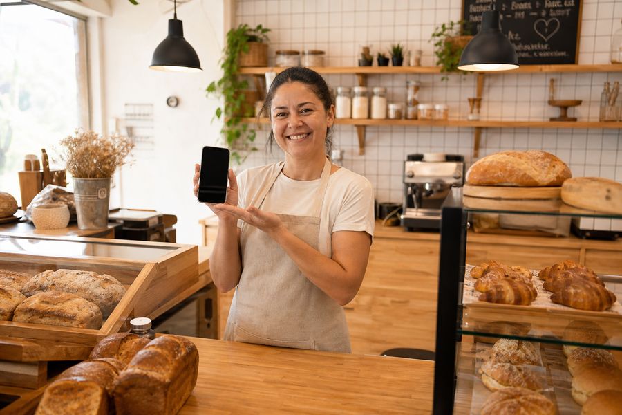 Dona da padaria com o negócio organizado e o celular na mão